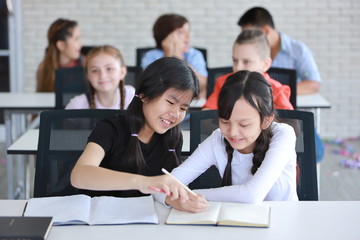 Fototapeta premium Two smart girls sitting and studying in classroom (education concept)
