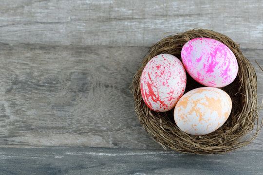 Group colorful and decorated easter eggs in bird nest on vintage wooden table background. Advertising image Easter or food concept with free space.