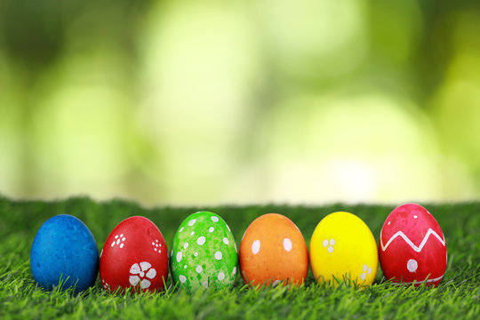 Group colorful and decorated beautiful easter eggs on green grass in nature with green bokeh background. Advertising image Easter festival concept with free space.