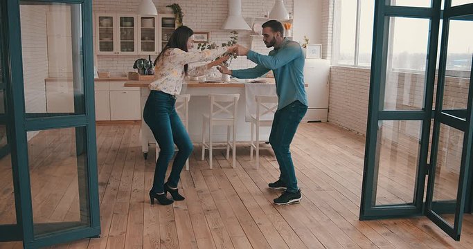 Beautiful couple dancing at home, Young man and woman cheerful  in kitchen. Loving people spending time together in their apartment. 4K slow motion