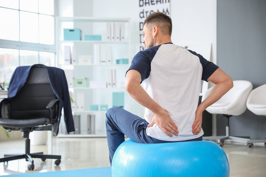Man doing exercises with fitness ball in office