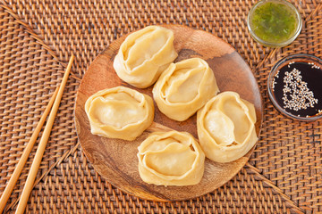 Plate with oriental dumplings and sauces on table