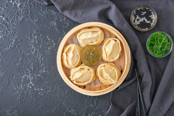 Steamer with oriental dumplings and sauces on dark background