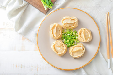 Plate with oriental dumplings and onion on table