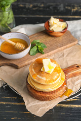 Tasty pancakes with honey and butter on table