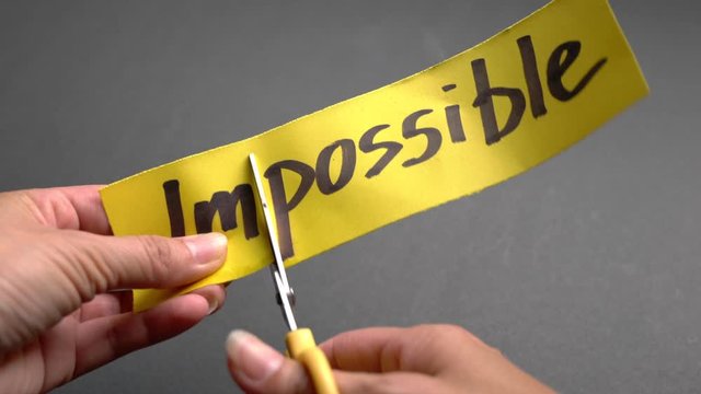 Woman cut the word Impossible to Possible. Self belief or think positive concept.