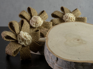 3 burlap flowers and birch tree wood pieces on a black and gray background.