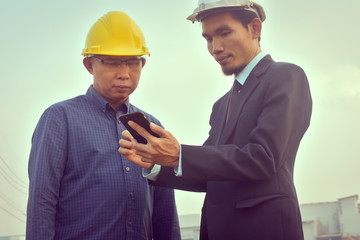 Contractor two people talking discussion looking at mobile smart phone to check inspection exclusive cooperation building construction