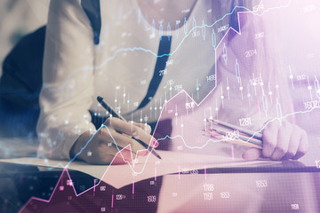 Double exposure of hands making notes with forex chart huds. Stock market concept.