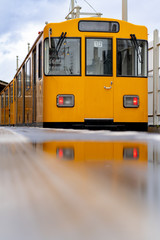a train of the Berlin Subway is in the historic station Berlin Warschauer Street. the train is reflected in a puddle after a rain, close up