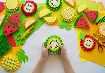 Fruit made of craft paper. Children's hands.