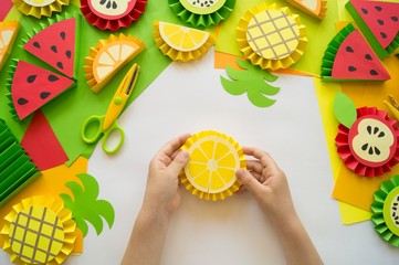 Fruit made of craft paper. Children's hands.