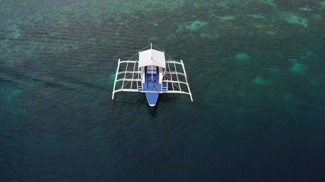 Aerial top down view of boat moving in open sea with clear and turquoise water on over coral reef,  Boat left the tropical lagoon, Moalboal, Oslob, Cebu Island, Philippines, 4K.