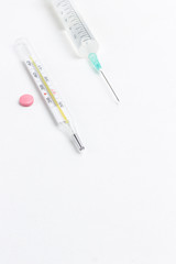 Thermometer and  syringe on white. Medical concepts and medicines