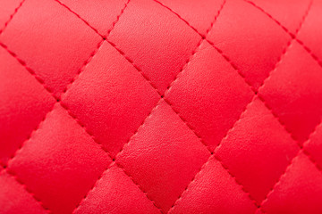 Fototapeta premium red leather pattern stitched squares with thread seam, decorative texture of animal skin, side view.