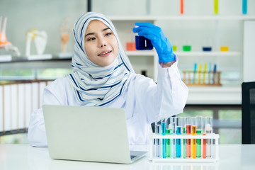 Asian young Muslim scientist testing the chemical experiment in hospital laboratory. Professional scientific pharmaceutical chemist investigating and making experiment in laboratory.