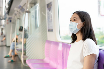 Beautiful young Asian woman wearing the protective mask while traveling in the city where fully with air pollution pm2.5. Unhealthy urban air pollution problem and coronavirus disease in Asia.