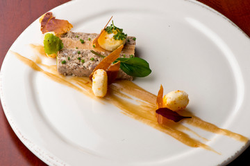 Duck Terrine. Traditional French cuisine a loaf of forcemeat or aspic, similar to a pâté, cooked in a covered pottery mold in a bain-marie.  Served at a French Bistro with potatoes and carrots