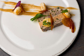 Duck Terrine. Traditional French cuisine a loaf of forcemeat or aspic, similar to a pâté, cooked in a covered pottery mold in a bain-marie.  Served at a French Bistro with potatoes and carrots