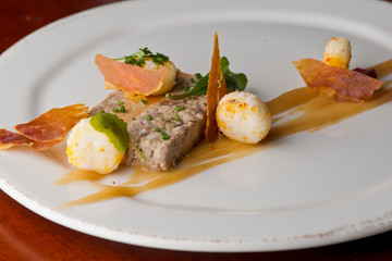 Duck Terrine. Traditional French cuisine a loaf of forcemeat or aspic, similar to a pâté, cooked in a covered pottery mold in a bain-marie.  Served at a French Bistro with potatoes and carrots