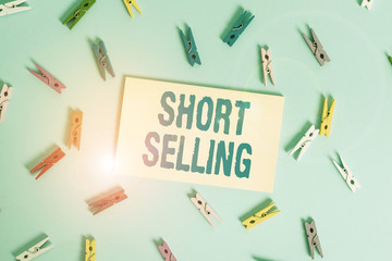 Conceptual hand writing showing Short Selling. Concept meaning Act of selling an asset that you do not currently own Colored clothespin rectangle shaped paper blue background