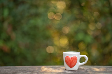 Cup coffee on wooden table, spring nature bokeh background.