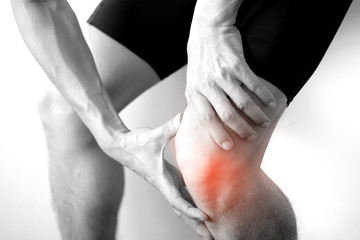 Black and white picture .Knee pain .man stand hand caught at the knee.  health concepts