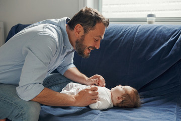 Proud Caucasian father talking to newborn baby girl. Smiling happy parent man with a daughter son....