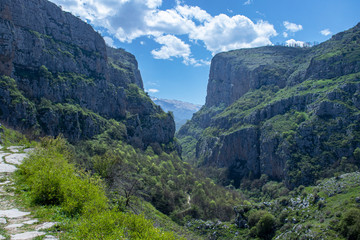 Fototapeta na wymiar Mountain landscape. A gorge of steep mountains through which a blue sky is visible. The mountains are covered with green vegetation.