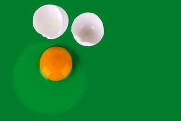 Raw egg, yellow yolk and white shell eggs on green background top view close up, uncooked broken egg backdrop, Easter banner, creative paschal poster, food wallpaper concept, trendy design, copy space