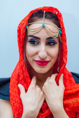 Beautiful eastern woman with makeup and jewelry wearing headscarf.