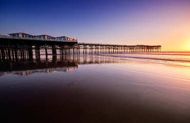 Fototapeta premium Obserwatorzy zachodu słońca na końcu Crystal Pier w Pacific Beach czekają, aż słońce zajdzie