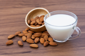 Almond milk with almonds seed in wooden bowl isolated on wood table background.