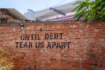 Until debt tear us apart message spray painted political protest message on brick wall