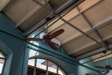 Wooden ceiling fan high in stylish blue warehouse with white ceilings
