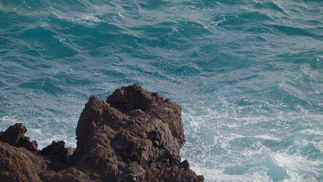 Storm in the Atlantic Ocean Waves Break the rocks of the shore Water turns into Foam Droplets and Splashes Clear Blue water of the Sea. Gale Tide is playing with the Sun shot slow motion URSA 4.6K
