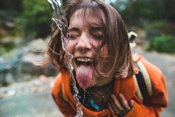 Girl drinks water with his tongue hanging out. © zhukovvvlad