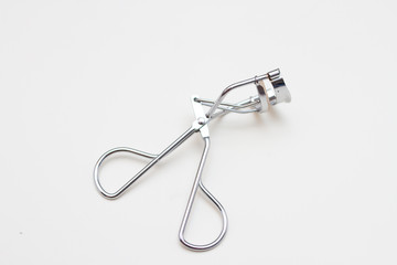 silver eyelash curlers on white background