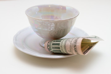 Close-up of plate with cup and bill tip on white table