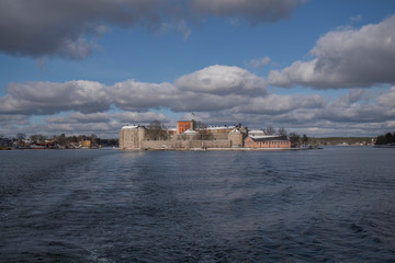 Fototapeta na wymiar Snowy winter view over the fort Vaxholms fästning in the Stockholm archipelago suburb Vaxholm a cold sunny day.