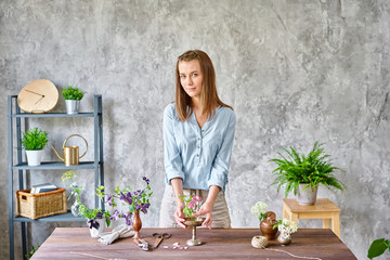 A young woman florist create flower arrangement Ikebana in kenzan. Uses scissors and pruner. Seasonal summer garden flowers.