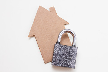 Concept of a cardboard house and a padlock on white background. House Security.