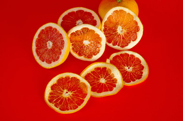 Chips of dried grapefruit sliced in thin circles, shot on a red background. Background for vegetarianism, healthy and wholesome food.