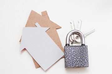Cardboard houses signs and padlock with metal keys on a white background.