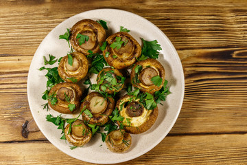 Baked mushrooms in plate on wooden table. Top view
