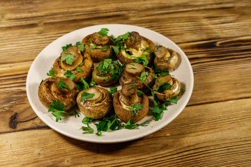 Baked mushrooms in plate on wooden table