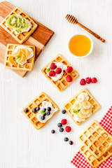 Fototapeta na wymiar Belgian waffles with creamy cheese and berries on white background top-down