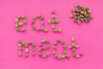 The inscription "eat meat" from pieces of food on a pink background. The view from the top