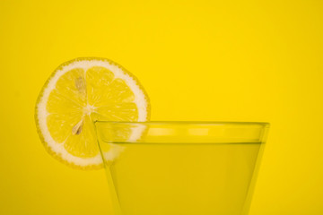 Glass of fresh lemon juice on a yellow background. Copy space.