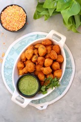 Moong dal ke pakode, ram laddoo, bhajias, Moongode or fritters. served with green mint and coriander chutney. Served over light background. Selective focus. with copy space.